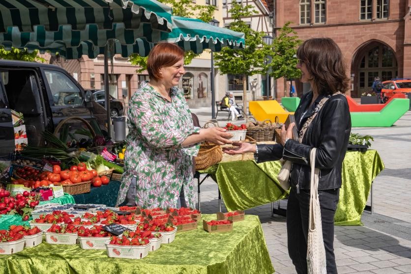 Besucher des Wochenmarktes auf dem Marktplatz beim Einkaufen.